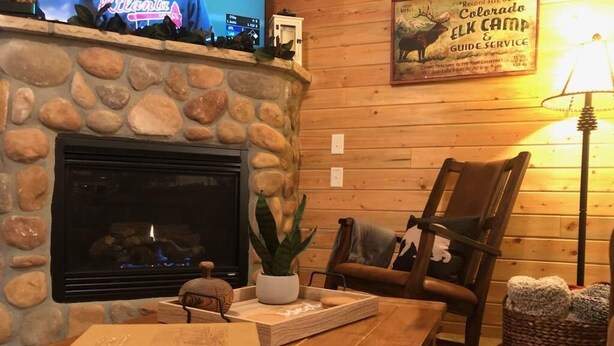 A cozy room with a stone fireplace, a wooden table with books, a comfortable chair, and a lamp. - Summer Sale: Mountain Retreat in Grand Lake (Grand Lake)