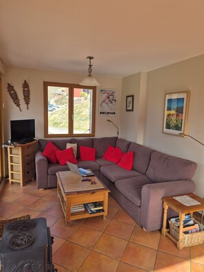 A living room with a sectional sofa, a wooden coffee table, a television on a stand, and a window with a view of the outdoors. - Cosy Chalet in the Real Alps near Annecy.
Relax, chill, walk, cycle, trek, ski. (Le Châtelard)