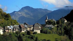 Un village avec des maisons traditionnelles, une église et des montagnes en arrière-plan.
