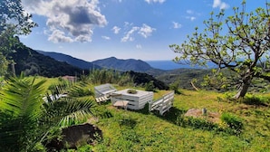 A scenic outdoor area with a view of mountains and the sea, featuring outdoor seating and greenery. - Apartment in a rustic atmosphere with sea views (Villanova)