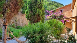 A rustic building with a stone exterior, surrounded by lush greenery and flowering plants. - Apartment in a rustic atmosphere with sea views (Villanova)