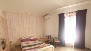 A bedroom with a bed, a small table, two chairs, a nightstand, and a window with curtains. - Apartment in a rustic atmosphere with sea views (Villanova)