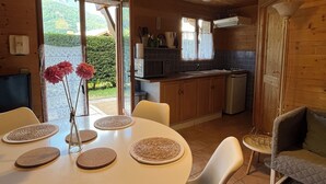 Un interior de madera acogedor con una mesa de comedor preparada para cuatro personas, un sofá y una cocina con fregadero y estufa.