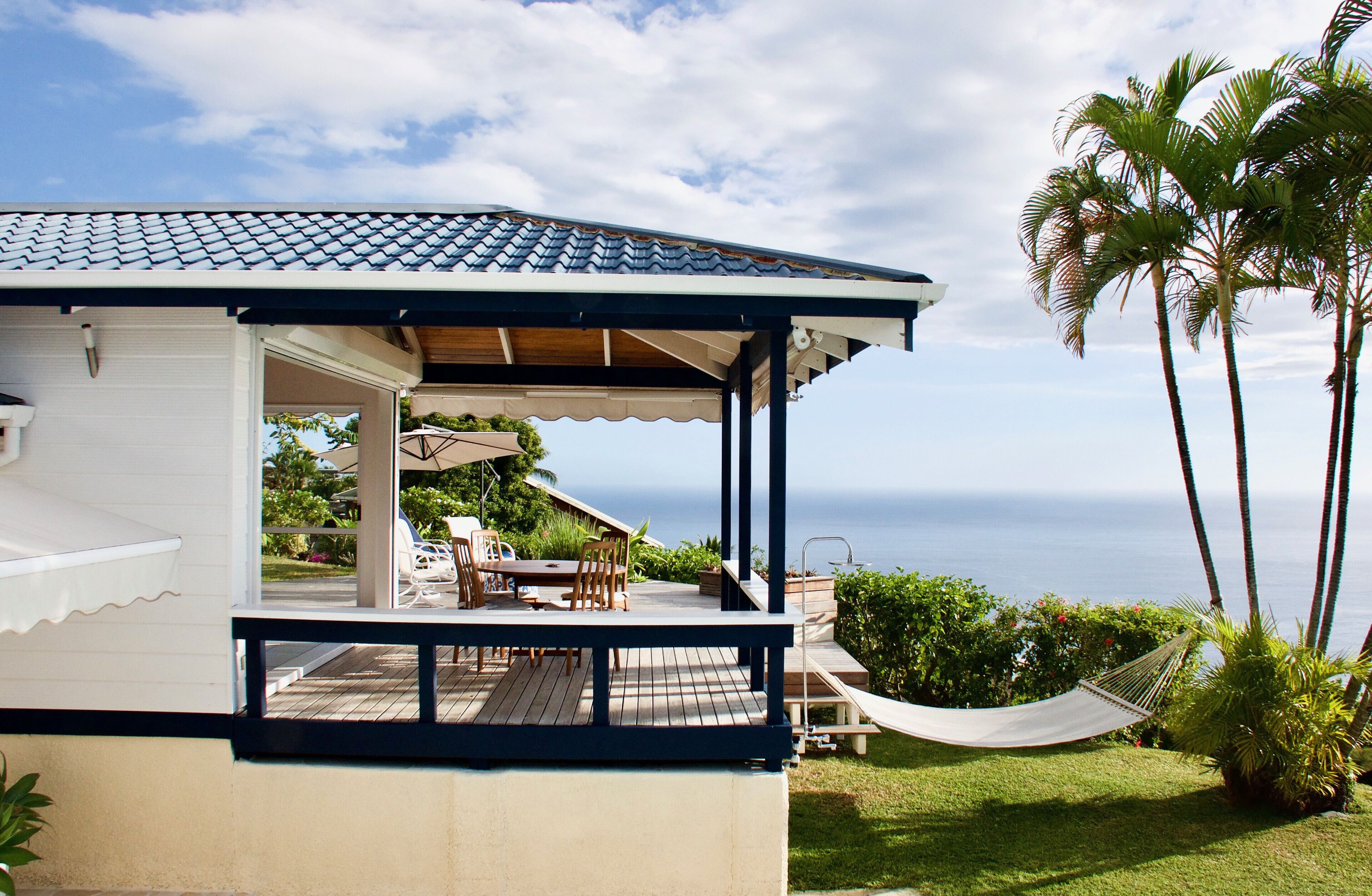 A house with a covered patio, a hammock, and a view of the ocean.