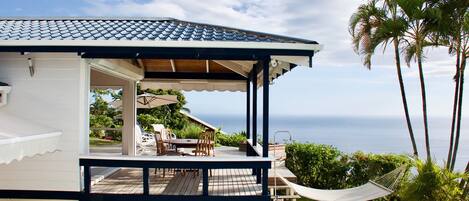 A house with a covered patio, a hammock, and a view of the ocean.