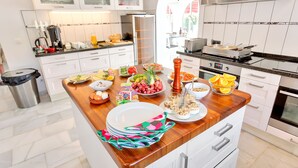 Een moderne keuken met witte kasten, een houten aanrechtblad en diverse etenswaren en keukenapparatuur.