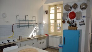 Una cucina con mobili bianchi, un frigorifero blu e diversi utensili da cucina appesi al muro.
