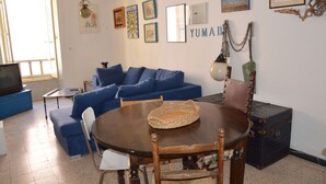Un soggiorno con un divano blu, un tavolo da pranzo in legno e una piccola televisione.