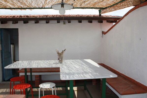 A patio with a white table, red and white chairs, and a hanging light fixture. - The Tower-house in the historical center of Sarzana (Sarzana)