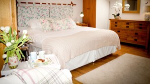 A bedroom with a large bed, wooden dresser, and a skylight.