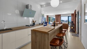 A modern kitchen with a wooden island, bar stools, and a view of the outdoors. - Holidayhome in a quiet location with pool&sea view, mini golf course& playground (Makarska)