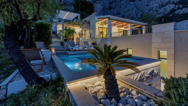 A modern house with a swimming pool, outdoor seating, and a mountain backdrop. - Holidayhome in a quiet location with pool&sea view, mini golf course& playground (Makarska)