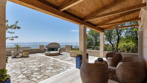An outdoor patio with stone flooring, wooden furniture, and potted plants. - Holidayhome in a quiet location with pool&sea view, mini golf course& playground (Makarska)
