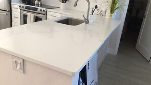A modern kitchen with a white countertop, stainless steel appliances, and a built-in sink.