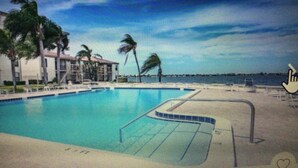 A swimming pool with a clear blue sky and palm trees in the background.