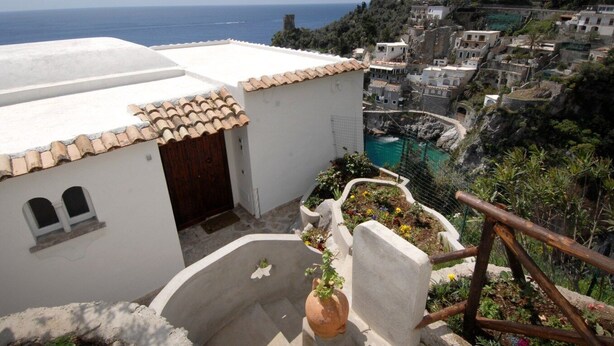 A coastal village with terracotta-roofed buildings, a small pool, and a view of the sea. - Blessed villa directly on the sea. (Praiano)