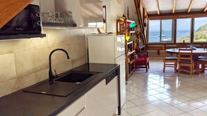 Eine Küche mit Spüle, einem weißen Kühlschrank und einem Essbereich mit Tisch und Stühlen.