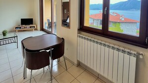 Ein Zimmer mit Esstisch und Stühlen, einem Fernseher und einem Fenster mit Seeblick und Bergblick.