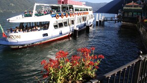 Ein Boot mit Passagieren, vertäut an einem Steg, mit Bergen im Hintergrund.