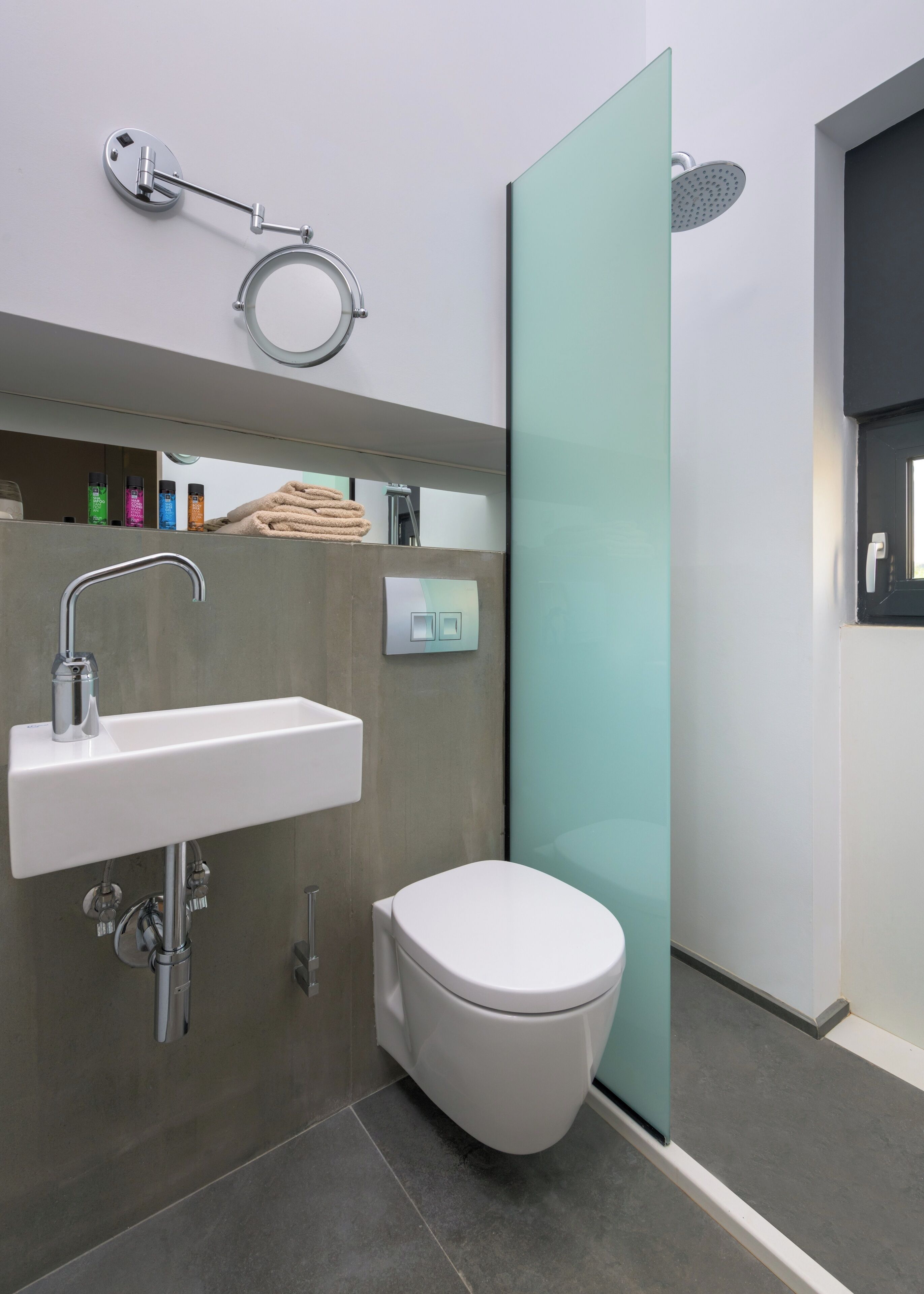 A modern bathroom with a white sink, a toilet, and a glass shower enclosure.