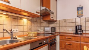 A kitchen with a microwave, oven, and coffee maker on the counter, a sink with a faucet, and wooden cabinets. - Pleasant and bright: The ground floor apartment with its ca. (Carolinensiel)
