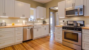 Une cuisine moderne avec des armoires blanches, des appareils en acier inoxydable et un plancher en bois.