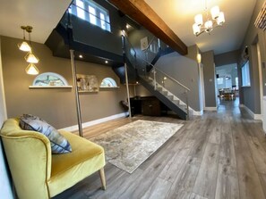 A spacious living area with a yellow armchair, a staircase, and a large window. - Amazing Family House Sleeps 12 with  Private Hot Tub in Tranquil Location (Holmfirth)