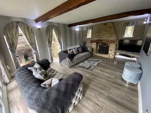 A cozy living room with a sofa set, a TV, and a fireplace. - Amazing Family House Sleeps 12 with  Private Hot Tub in Tranquil Location (Holmfirth)