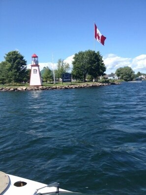 Un far al costat d'una calma extensió d'aigua, amb una bandera canadenca onejant.