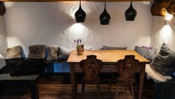 A cozy dining area with a wooden table and chairs, a bench with cushions, and pendant lights.