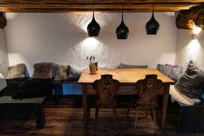 Ein gemütlicher Essbereich mit einem Holztisch und Stühlen, einer Bank mit Kissen sowie Pendelleuchten.