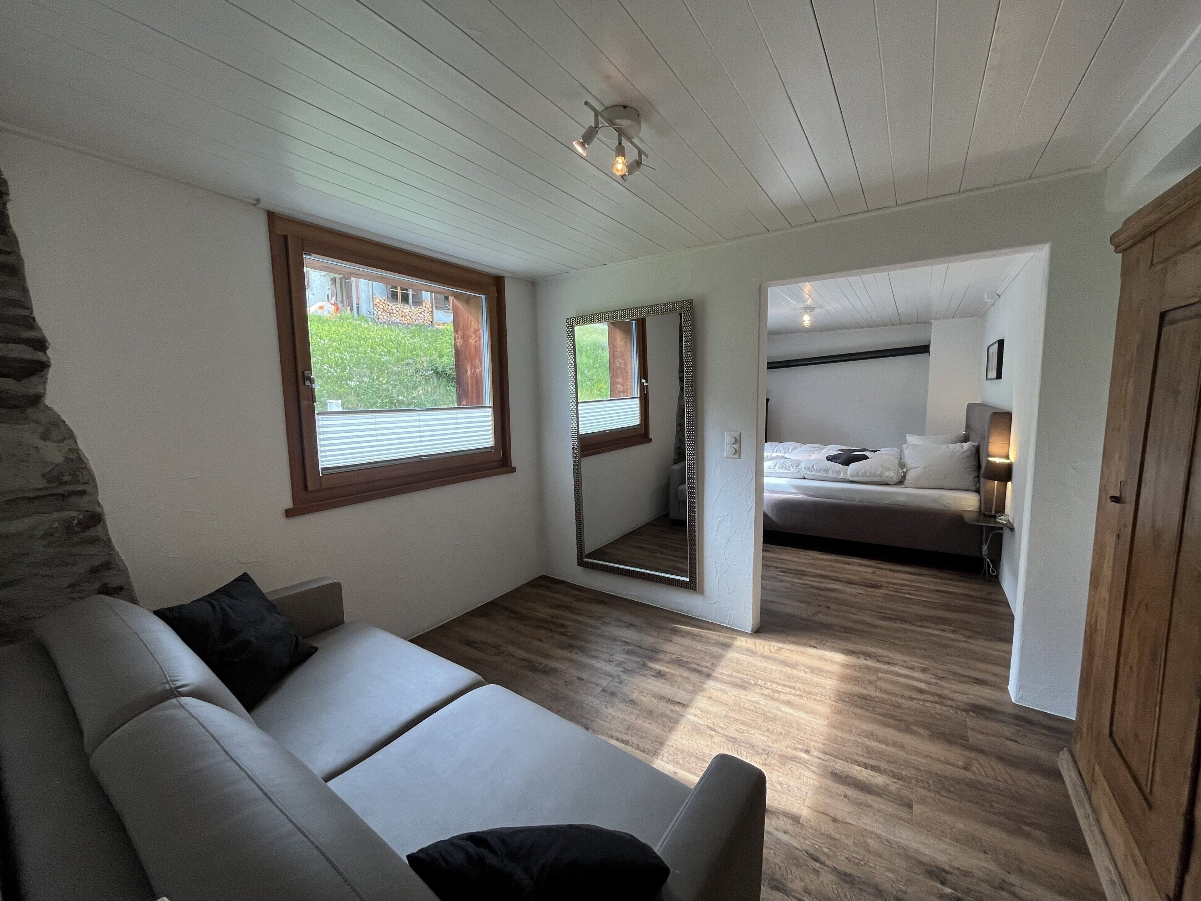 Une pièce comprenant un canapé, un lit, un miroir et une armoire.