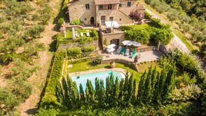 Une villa en pierre dotée d’une piscine, d’un espace salon extérieur et d’un jardin.