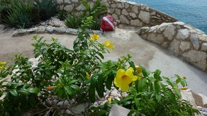 Un muro de piedra con un jardín delantero, con vistas a un cuerpo de agua.