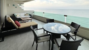 Un balcon avec vue sur la mer, aménagé avec un canapé, des fauteuils et une table.