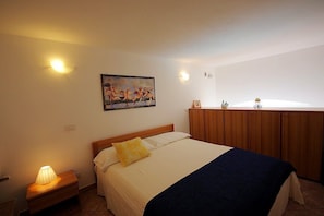Quarto com cama, luminária de cabeceira e um quadro na parede.