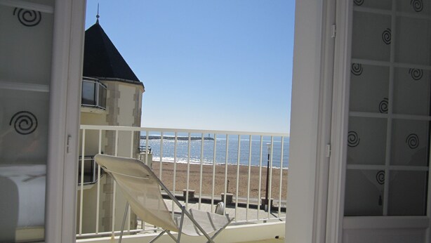 En balkon med udsigt over stranden og havet.