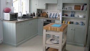 Een keuken met lichtblauwe kastjes, een magnetron, een waterkoker en diverse keukengerei.