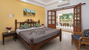 A bedroom with a bed, bedside table, and a window with an open door leading outside.