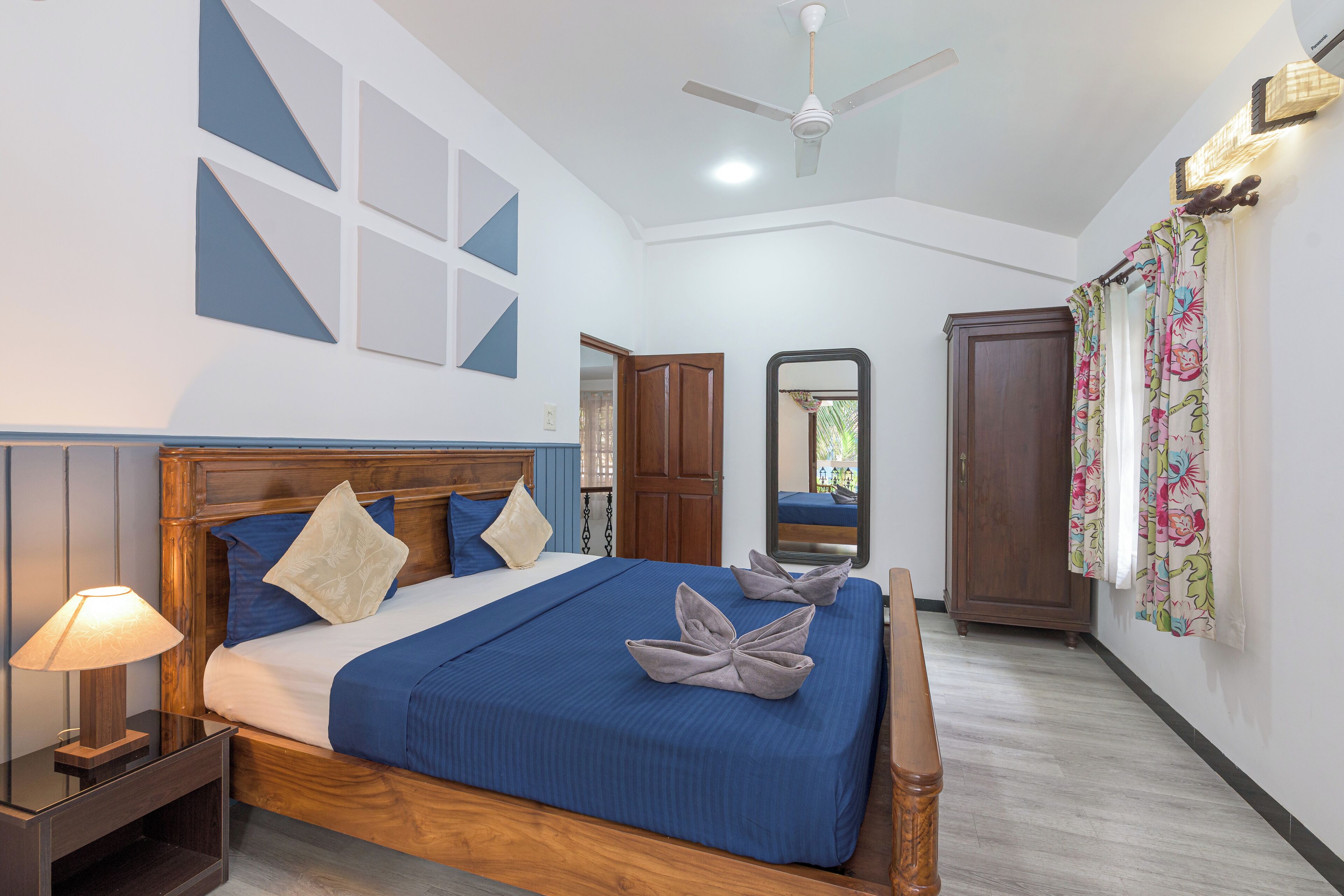 A bedroom with a wooden bed, a nightstand, a ceiling fan, and a wardrobe.