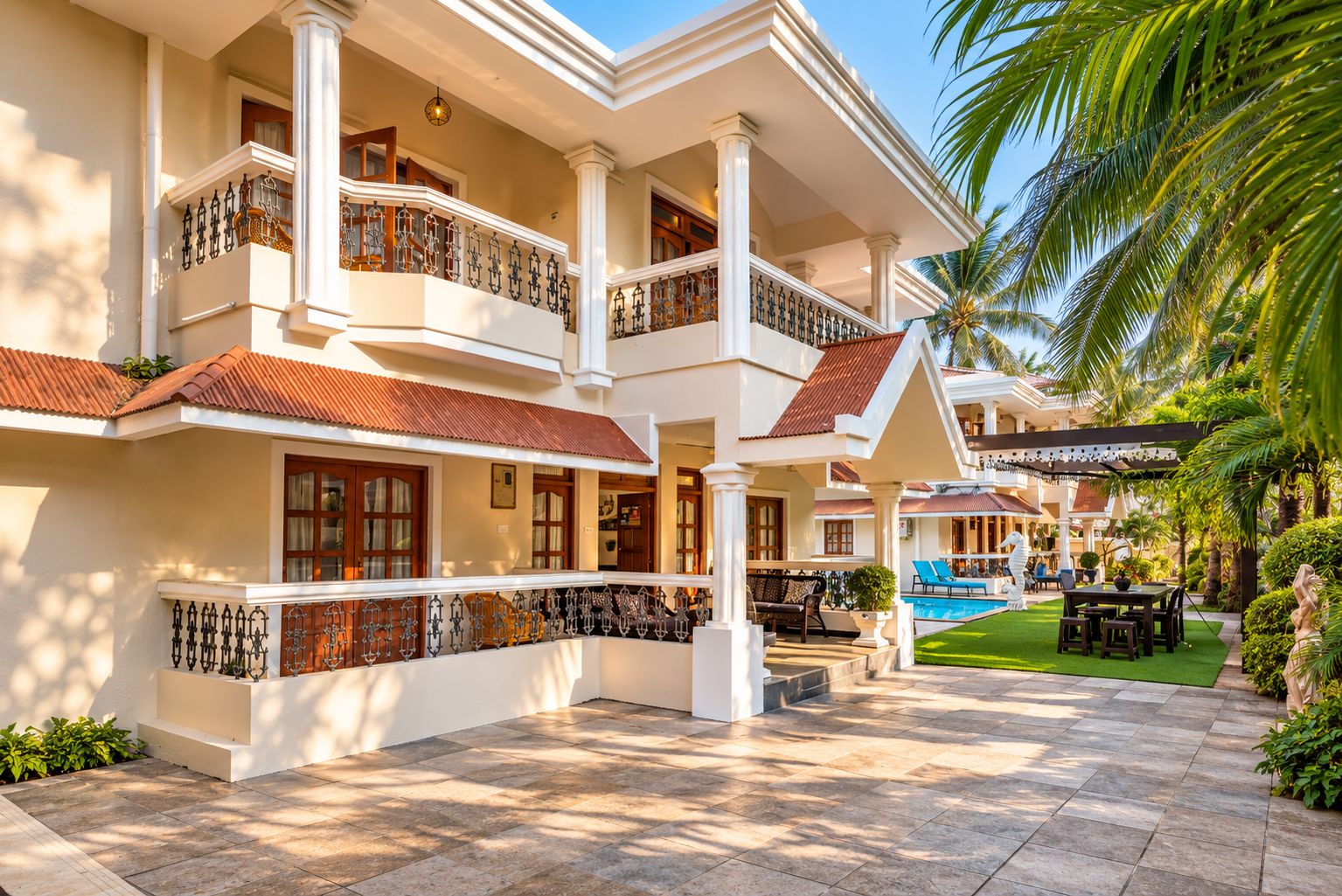 Un hotel de varios pisos con balcones, piscina y un jardín bien cuidado.