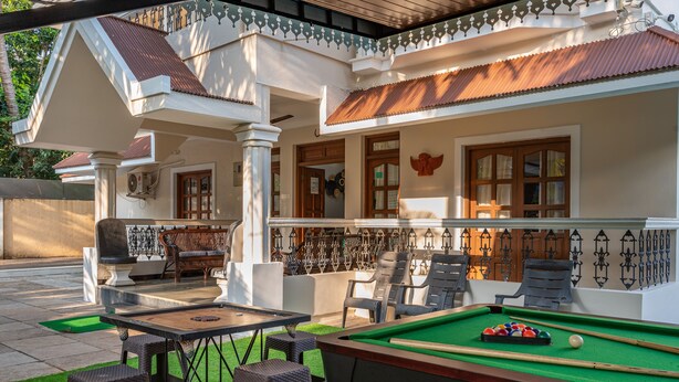 A pool area with a pool table, chairs, and a seating area with a table and chairs.
