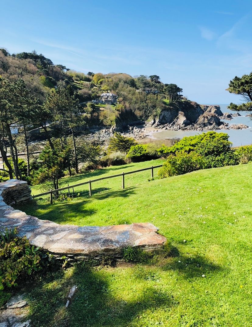 A grassy area with a stone pathway leading to a coastal view.