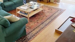 A living room with a green sofa, a coffee table, and a patterned rug. - Detached Cottage Overlooking The Sea (Lee)