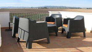A terrace with wicker furniture and a view of a field and mountains. - Townhouse With Uninterrupted Views (Torre-Pacheco)