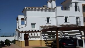 A multi-story white building with balconies, a car parked in the driveway, and a pergola over the entrance. - Townhouse With Uninterrupted Views (Torre-Pacheco)