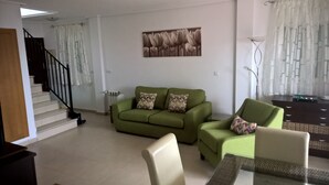 A living room with a green sofa, a coffee table, and a painting on the wall. - Townhouse With Uninterrupted Views (Torre-Pacheco)