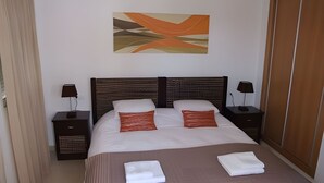 A neatly arranged hotel room with a large bed, two bedside tables with lamps, a wooden wardrobe, and a wall-mounted abstract painting. - Townhouse With Uninterrupted Views (Torre-Pacheco)