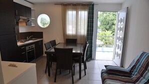 A compact living space with a kitchenette, dining area, and a sofa. - Alizé T3 for 6 people (San-Nicolao)