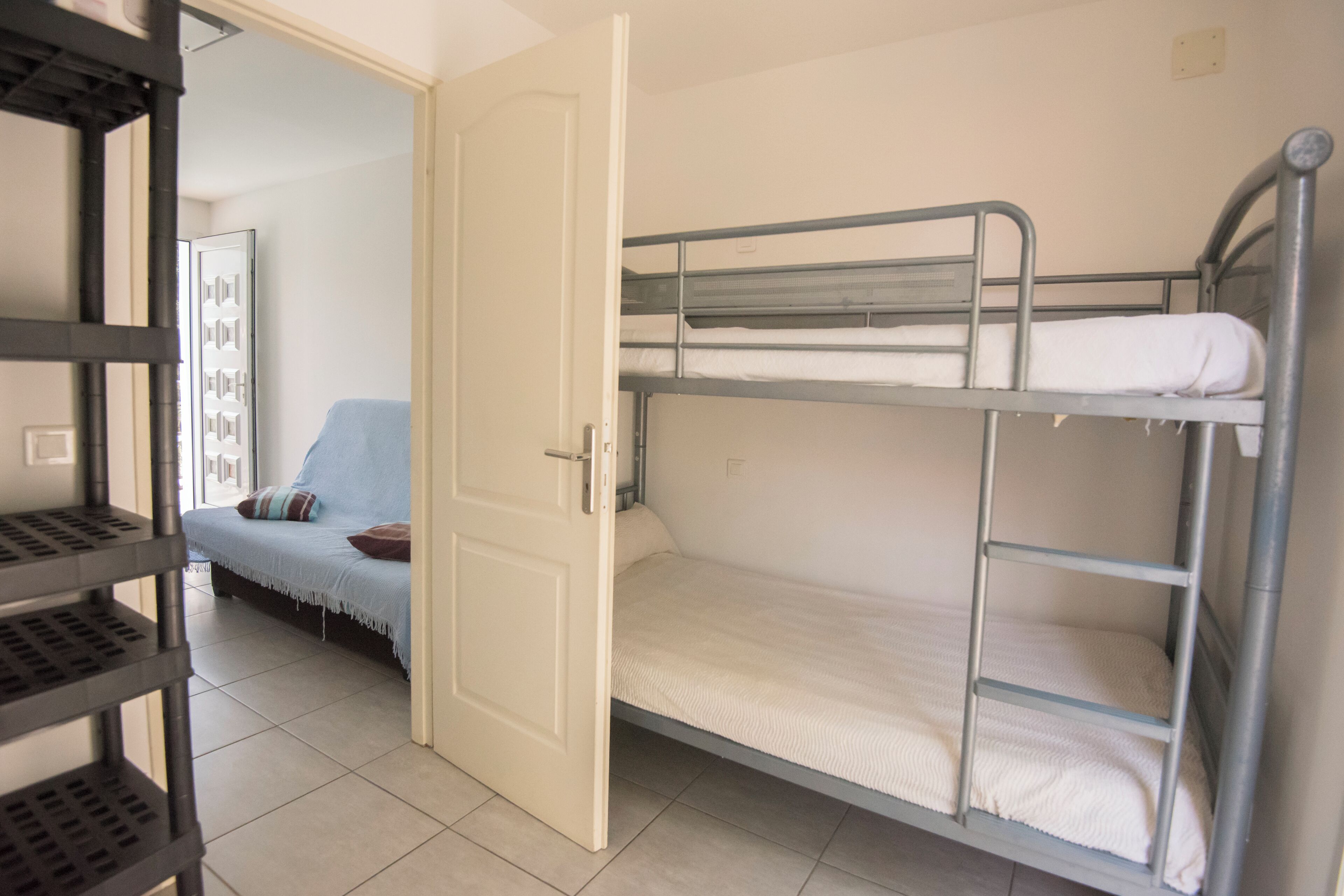 Une chambre avec des lits superposés et une porte donnant sur une autre pièce.